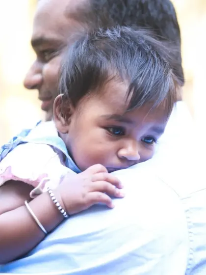 A quiet and gentle moment with a baby looking over her father's shoulder, her thoughtful expression beautifully captured.