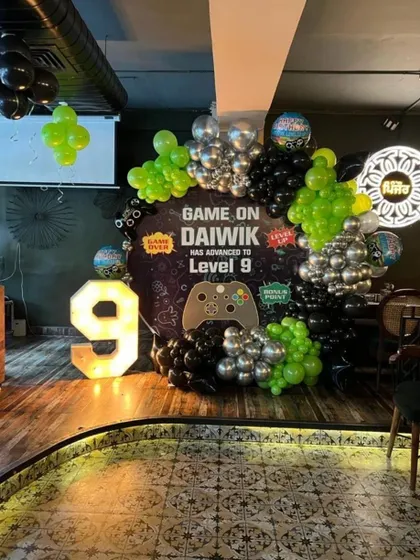 Game on! An epic Xbox and video game themed birthday party for a 9th birthday. The decoration features a custom 'Game On' backdrop, a balloon arrangement in gaming-inspired green, black, and silver, and a large light-up number '9'.
