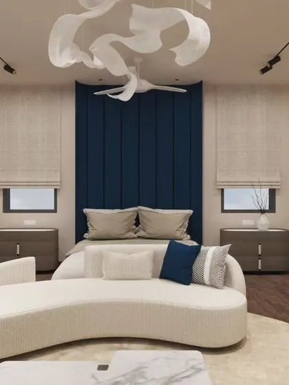 A contemporary bedroom where a deep blue upholstered headboard provides a rich pop of color. The sculptural ceiling light adds an artistic touch, while the curved chaise lounge offers a comfortable spot to relax. It's a balance of bold statements and soft comforts.