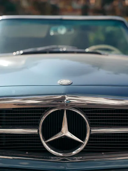 The iconic three-pointed star of a vintage Mercedes-Benz. This close-up on the grille emblem is a tribute to a legacy of automotive excellence.