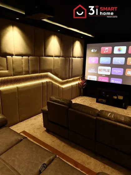 This wide shot captures the full design of the room, from the comfortable leather sofas to the large screen and the beautifully lit, custom-paneled walls.