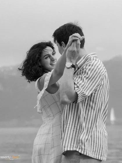 A dance by the lake. This timeless black and white portrait captures a moment of graceful movement and romance, their figures soft against the water.