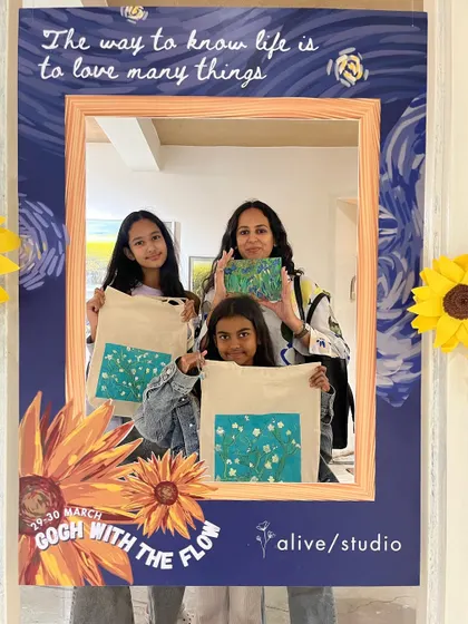 A family proudly displays their Van Gogh-inspired tote bags and paintings from our special event weekend.