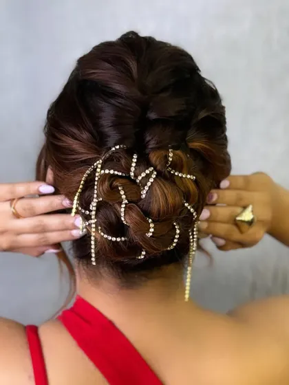 A modern and messy updo with a twist. This hairstyle is perfect for a cocktail party or reception, and we've added a sparkling hair chain for extra glamour.
