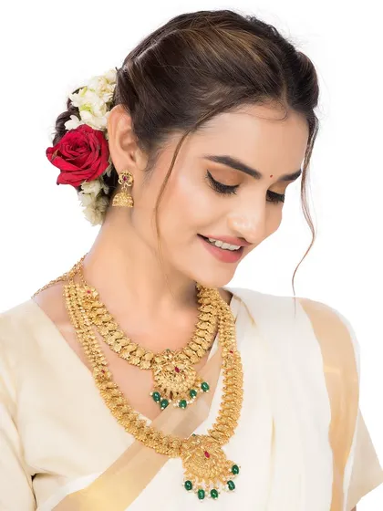 A smiling model wearing a layered gold temple necklace, showcasing the product in a positive and appealing context.