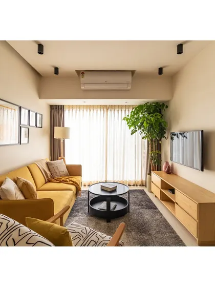 The full view of the living room, with its mustard sofa, abstract accent chair, and simple, functional TV console. The space is bright, airy, and full of personality.