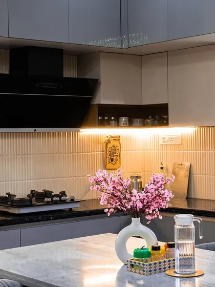 A detailed shot of a kitchen island with a marble top, perfect for meal prep or casual dining. The soft pink cherry blossoms in the vase add a delicate pop of color to the grey cabinetry.