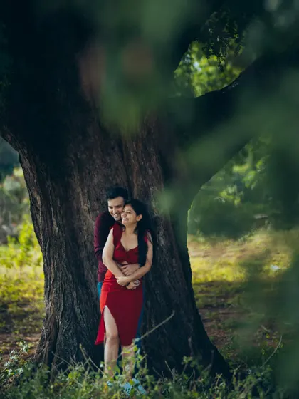A romantic embrace under a tree. This pre-wedding photo uses natural framing to create an intimate and secluded feel.