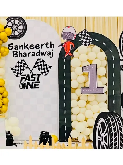 A personalized arch for Sankeerth Bharadwaj's "Fast One" birthday. The decor includes checkered flags, a racer cutout, and the child's name, making the theme feel extra special and customized.