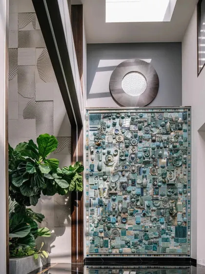 Here you can see the ceramic mural in context, placed in the double-height courtyard next to a textured sandstone panel. The sunlight from the skylight above highlights the intricate details of both artworks.