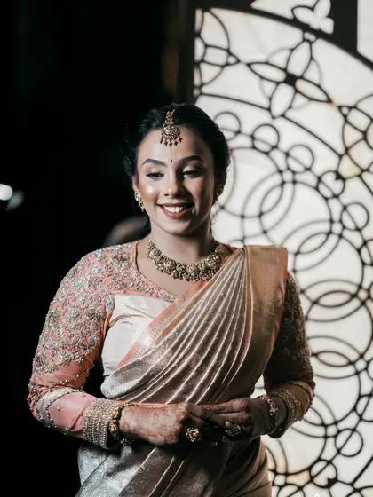 The bride posing against a dramatic background, looking confident and beautiful in her custom peach organza blouse.
