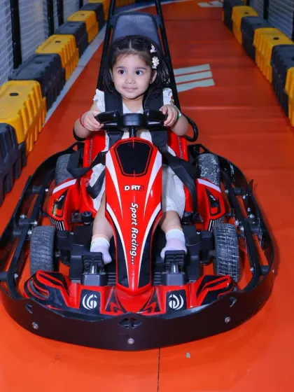 A young racer poses for a photo before her big race. The track is lined with safety barriers for a worry-free experience.
