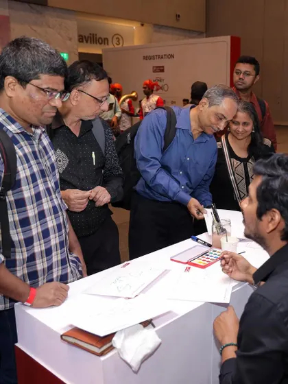 Interacting with an attendee at the IDFC First Bank event. I love hearing people's stories and translating them into a small piece of art they can take home.