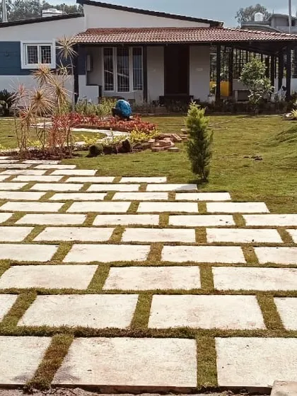 The entrance to a modern farmhouse with newly laid stone paving and fresh turf grass being installed. This shows a project in the final stages of hardscape and softscape integration.