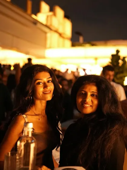 Two guests enjoying the ambient lighting and sophisticated vibe of the rooftop bar.