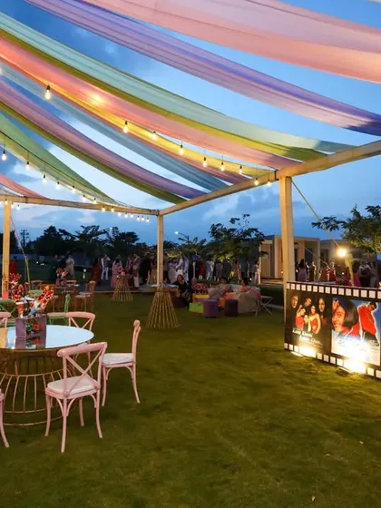 An outdoor setting offers endless creative opportunities. For this Sangeet, we used colorful drapes, a Bollywood movie poster bar, and playful table decor to transform a simple lawn into a vibrant and festive party space.