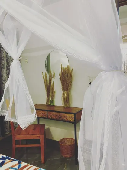 A sneak peek of the apartment's decor in daylight, featuring a stylish console table, dried pampas grass, and the elegant sheer curtains of the cabana bed.