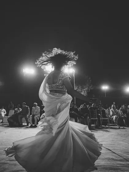 A bride twirling on the dance floor, captured in black and white. The motion blur of her dress and the backlighting create a dynamic and artistic image of her joyful performance.