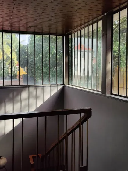 Sunlight streams through the large windows of the staircase, creating patterns of light and shadow. The design ensures that every part of the house, including circulation spaces, feels bright and connected to the outdoors.