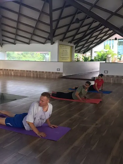 Guests practice Bhujangasana (Cobra Pose) in the yoga hall. This gentle backbend strengthens the spine, opens the chest, and helps to relieve stress and fatigue.