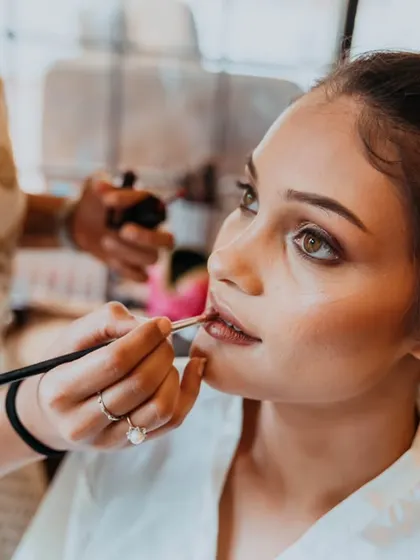 The final touches of makeup being applied, a key moment in the bride's transformation.
