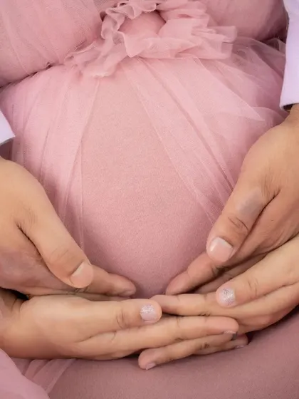 A beautiful close-up of both parents' hands cradling the baby bump. This shot is all about connection, protection, and the love that surrounds this new life.