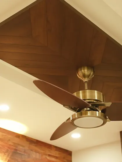 A close-up of a ceiling design featuring a wooden panel in a herringbone pattern with an antique-finish fan. This detail adds texture and character to the room from above.