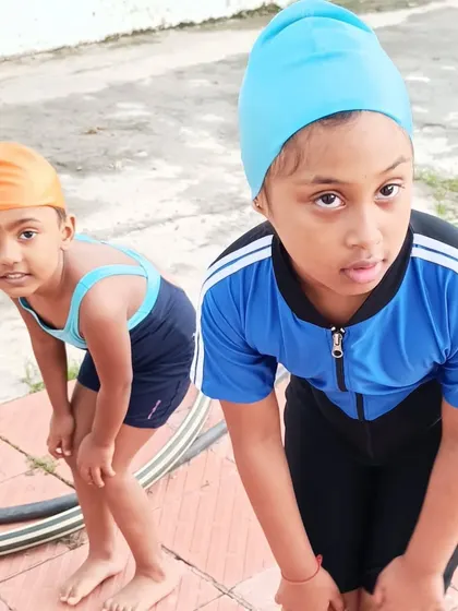 Two young swimmers getting ready for their warm-up exercises by the pool.