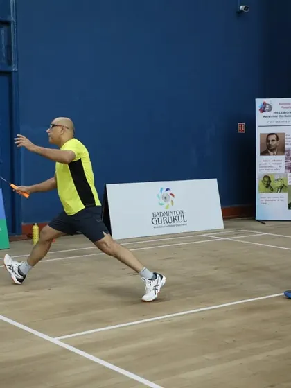 An adult player lunges for a defensive shot, showcasing the fitness and flexibility gained from regular play.