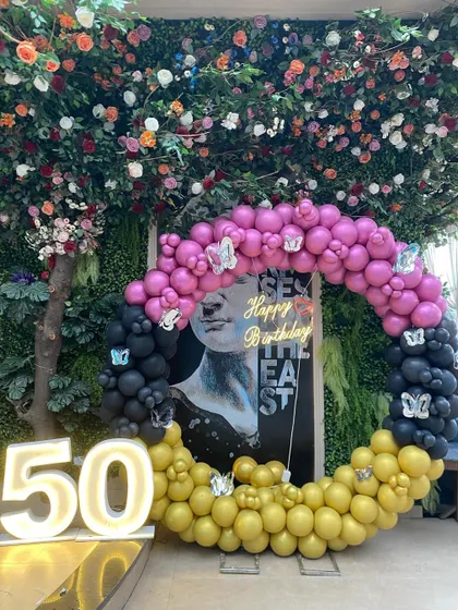 The butterfly details on the balloon arch add a touch of whimsy to this bold and modern 50th birthday decoration.