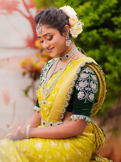 A side view of the dark green velvet blouse, showing the detailed paisley embroidery and delicate tassels on the sleeve. Please note the saree is not for rent.