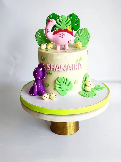 A full view of the cute dinosaur cake. The design is playful and perfect for a child who loves dinosaurs but prefers a softer, more colorful aesthetic.