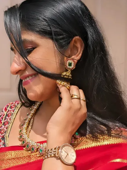A candid shot of a client enjoying her look, wearing a simple Jadau necklace and matching jhumkas.