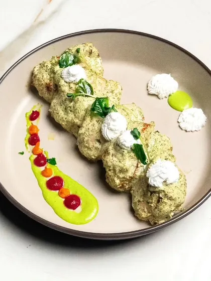 A plate of our creamy malai tikka, garnished with microgreens and colorful sauces. This is an example of our modern plating style.