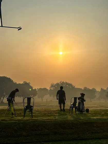 Silhouettes of golfers against the hazy sunrise, a peaceful and inspiring start to the day.