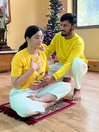 An instructor guides a student in proper yogic breathing, a fundamental part of our beginner course that helps calm the mind.