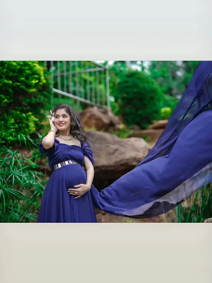 The beauty of a simple, flowing gown. The fabric of this dark blue dress catches the air, adding a sense of movement and grace to this outdoor solo portrait.