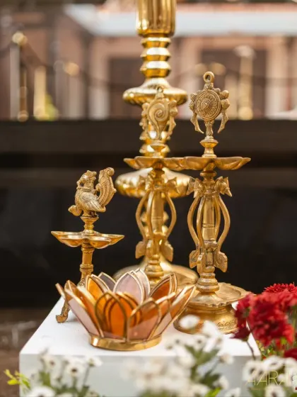 A collection of ornate brass lamps and a lotus-shaped candle holder. These beautiful artifacts were key elements in our 'Divya Stambh' theme, adding a warm, sacred glow to the space.