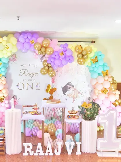 I created this fairytale-themed setup with a soft pastel balloon arch and gold accents. The decor includes a personalized backdrop, light-up number '1', and decorative fences for a storybook feel.