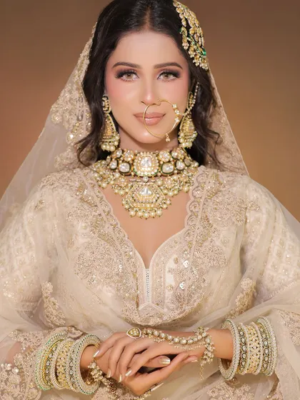 A regal look in a pearl white lehenga. The heavy, matching jewellery set with a passa gives it a complete, royal Muslim bride look.