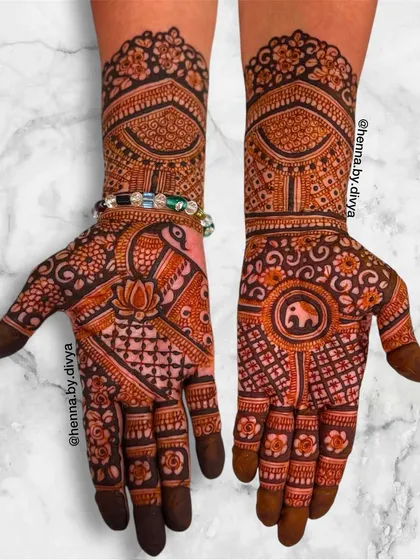 A rich design combining peacock and elephant motifs. The central elephant is surrounded by intricate floral patterns, while the other hand features a peacock.