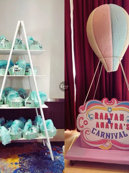 A giveaway station with party favors in baskets, next to a hot air balloon-themed sign for the carnival.