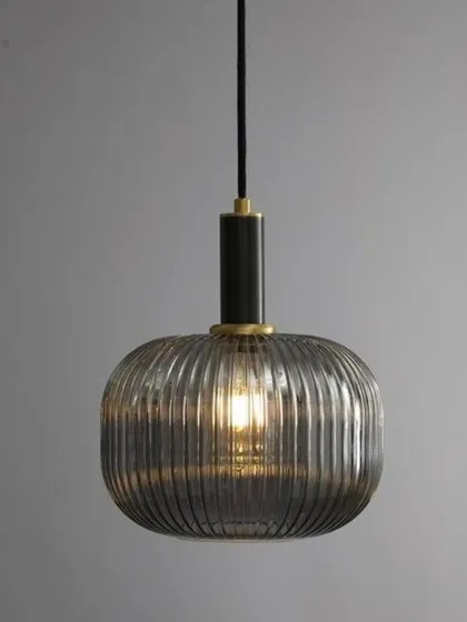 The Cordelia pendant shown in a grey, smoked glass finish with black and brass hardware. This color variation offers a cooler, more contemporary mood while maintaining the elegant ribbed glass texture.