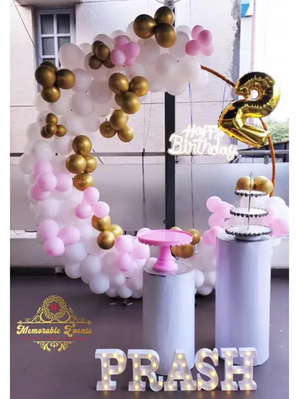 A second birthday party setup with a pink and gold balloon ring.