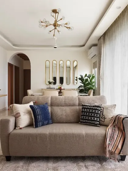 An overview of the open-plan living room, designed for a young couple who loves to host. The space incorporates TV, crockery, and pooja units with a cohesive design language of curves and grooves.