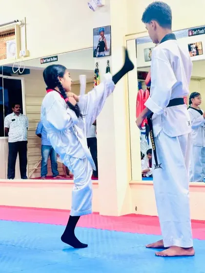 A young girl demonstrates an impressive high kick during target practice.