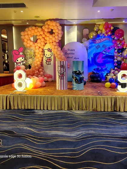 A full stage view of the dual-theme birthday party. This shows how I balance two different designs, Hello Kitty and Hot Wheels, using separate color schemes and backdrops while creating a cohesive look with light-up numbers for the ages.