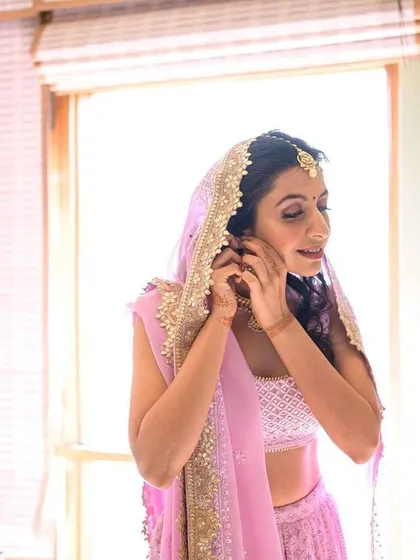A candid moment of the bride putting on her earrings, one of the final touches.