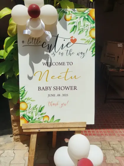 A custom welcome sign for a baby shower with a "little cutie" orange theme, placed on an easel to greet guests at the entrance.