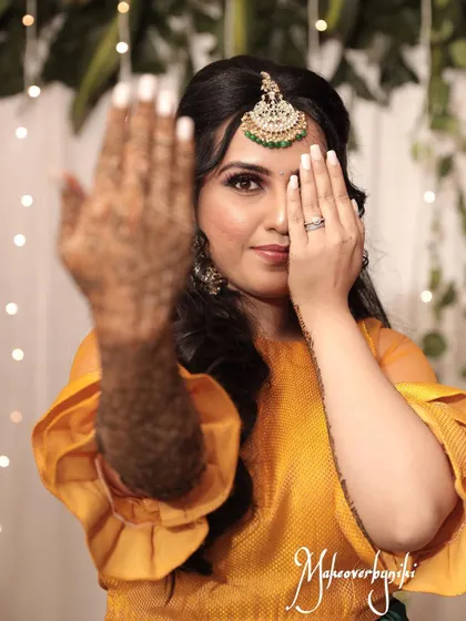 Chinmayi showing off her intricate mehendi design. Her makeup is fresh and radiant, perfect for the fun and festive atmosphere of a mehendi event.
